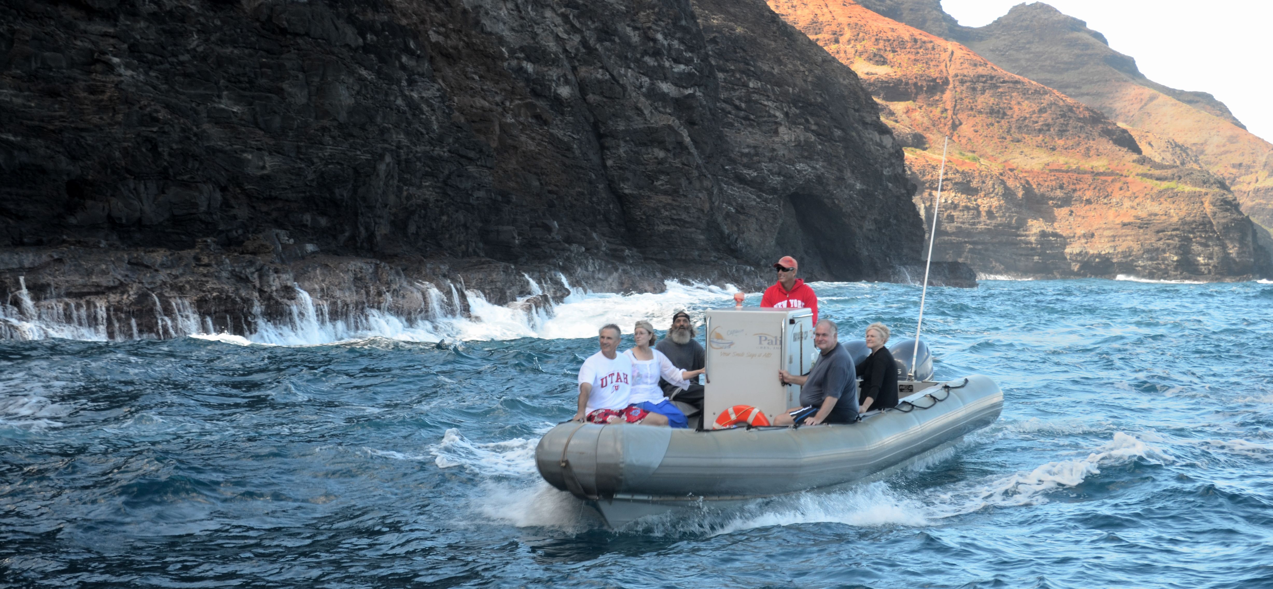 A full Zodiac raft with guests and crew traveling beside the Na Pali Coast